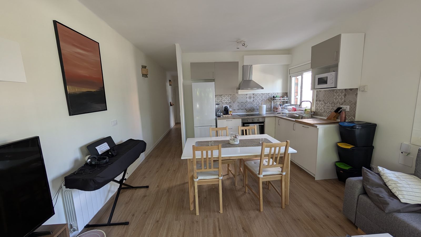Salón reformado con la cocina abierta y suelo de madera clara