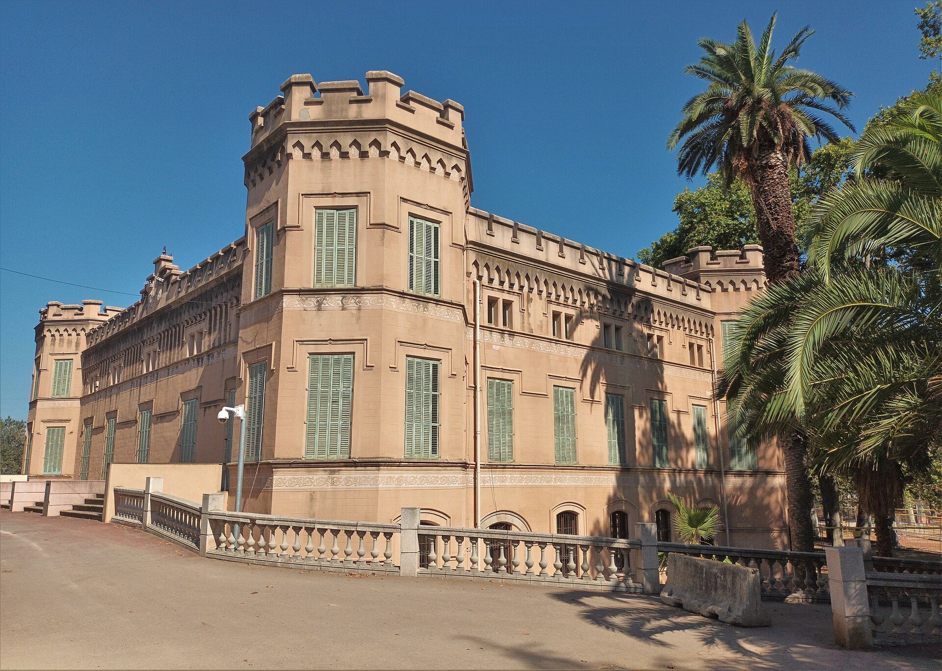Palau de Can Mercader, en Cornellà de Llobregat, con sus torres almenadas y las palmeras del parque