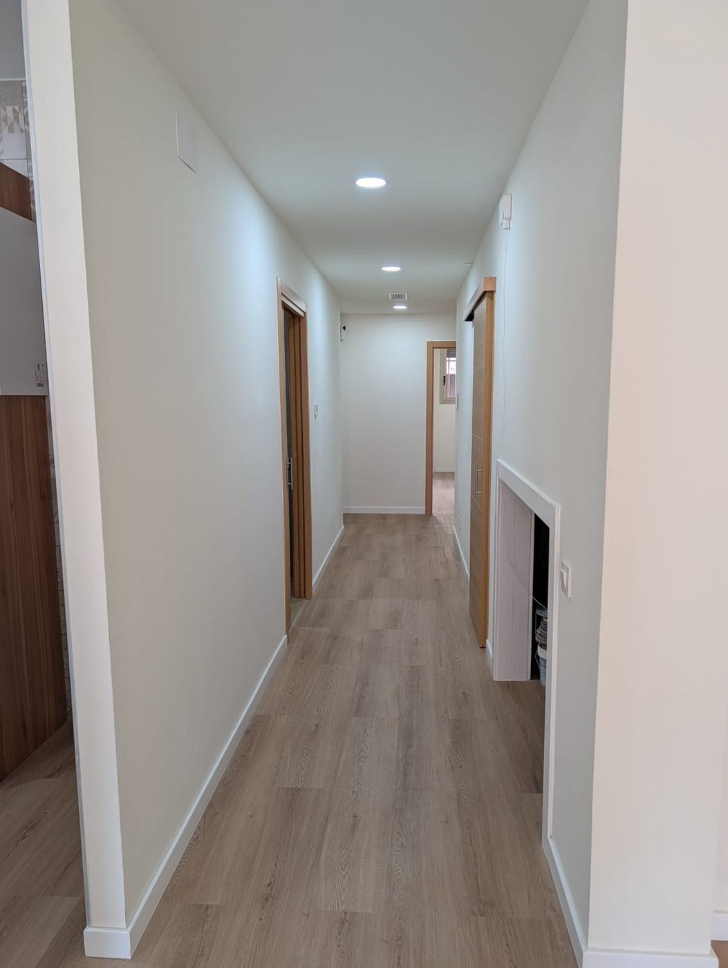 Pasillo terminado, ancho y sin resaltes, con suelo de madera